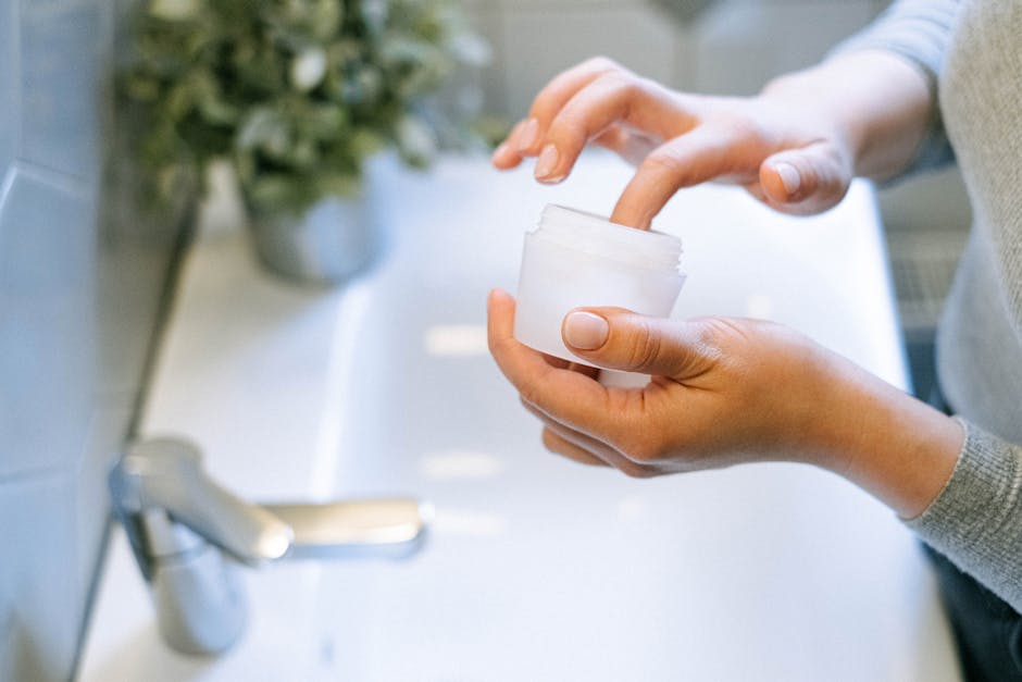 Close-up of woman's hands applying face cream, emphasizing self-care routine.