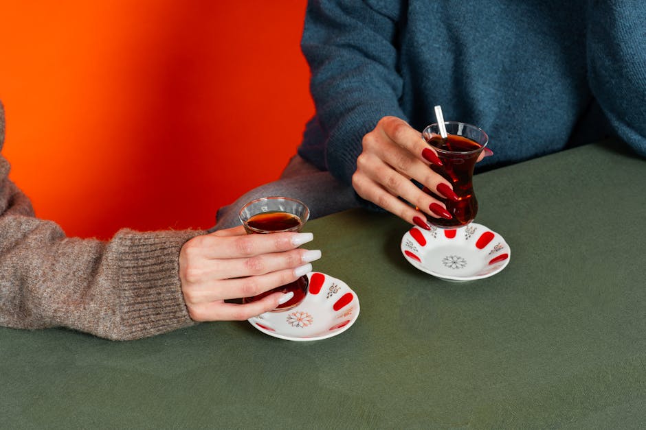 Close-up of women holding Turkish tea glasses with distinct design.