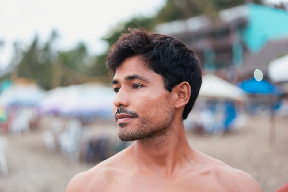 A contemplative young man with a blurred beach background, conveying tranquility and freedom.