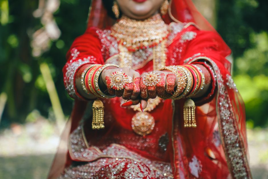 Indian bride displaying detailed henna, gold jewelry, and traditional attire. Captivating cultural elegance.