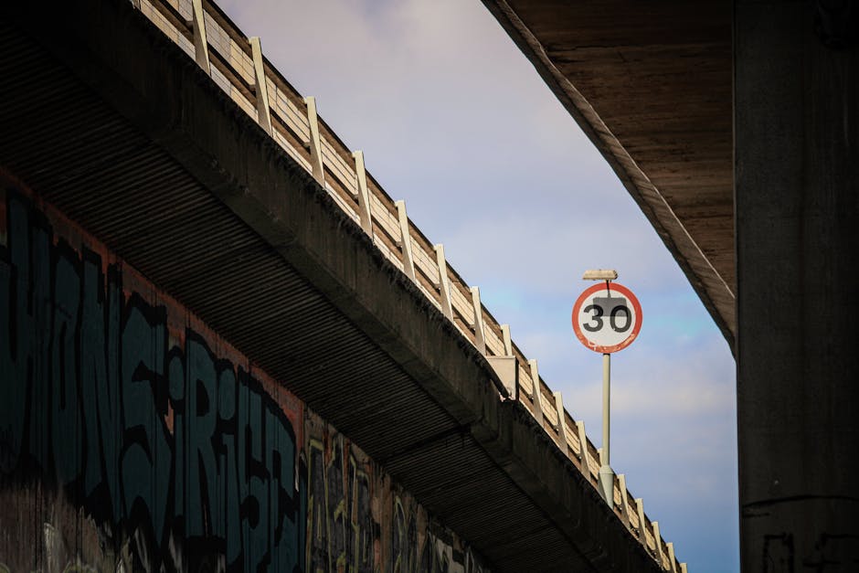 Low angle view of urban bridge featuring graffiti and a prominent speed limit sign.