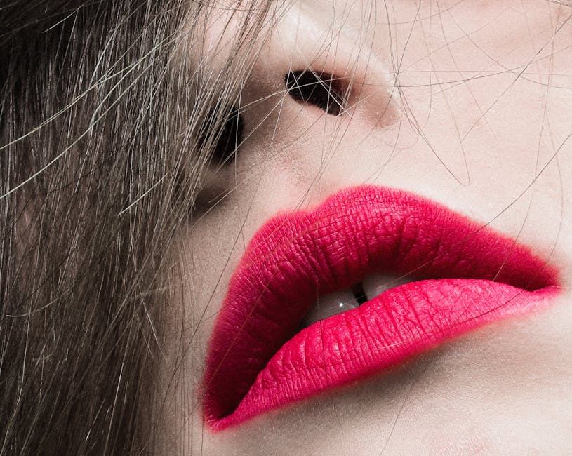 A striking close-up photo of lips with vivid red lipstick and loose hair strands, focusing on beauty.