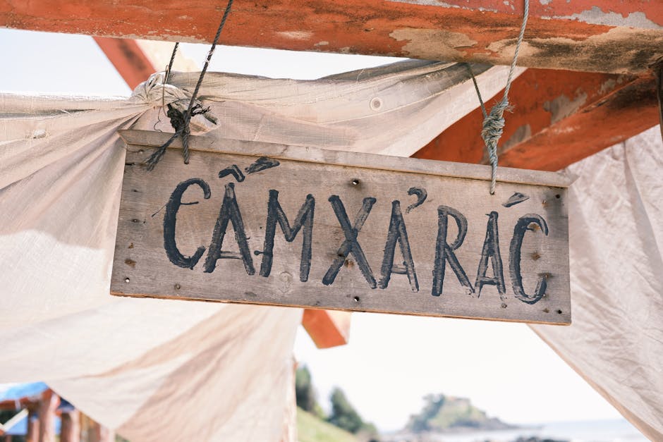 Hanging wooden sign with Vietnamese text outdoors, conveying a rustic and worn appearance.
