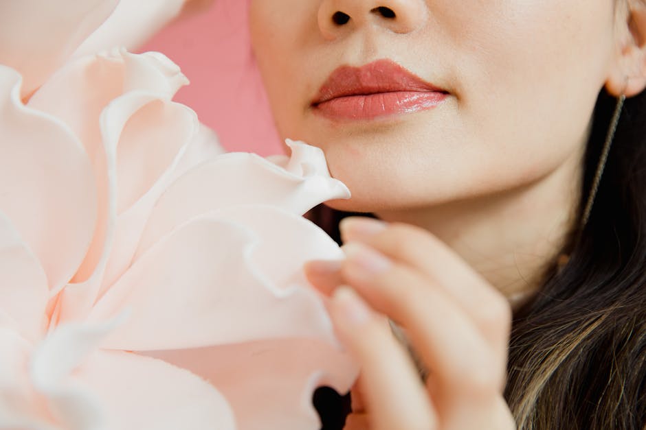 Close-up of a woman's lips with a pink flower, highlighting beauty and elegance.