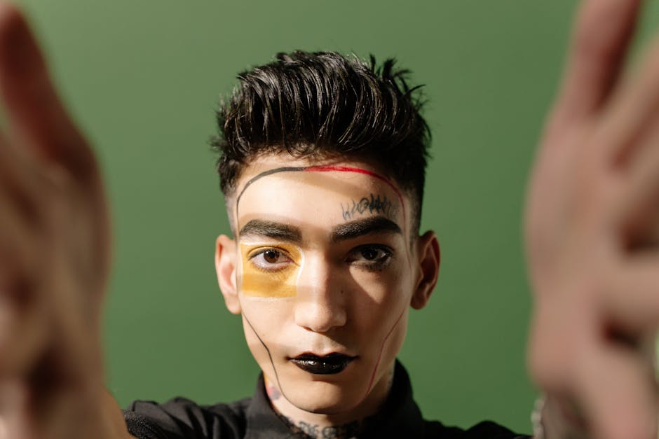 Creative portrait of a young man with a painted face on a green background, showcasing modern artistry.