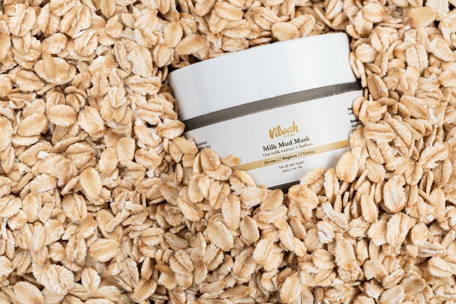 Top view of Vilvah Milk Mud Mask jar surrounded by rolled oats for skincare and wellness.
