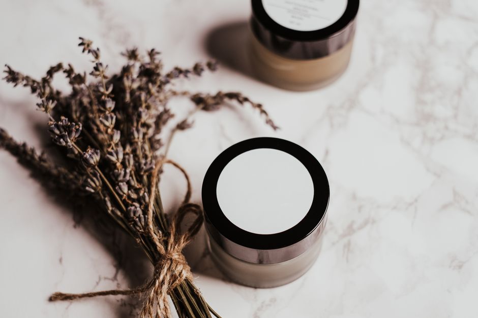 Aesthetic arrangement of skincare products and lavender on marble for beauty promotion.